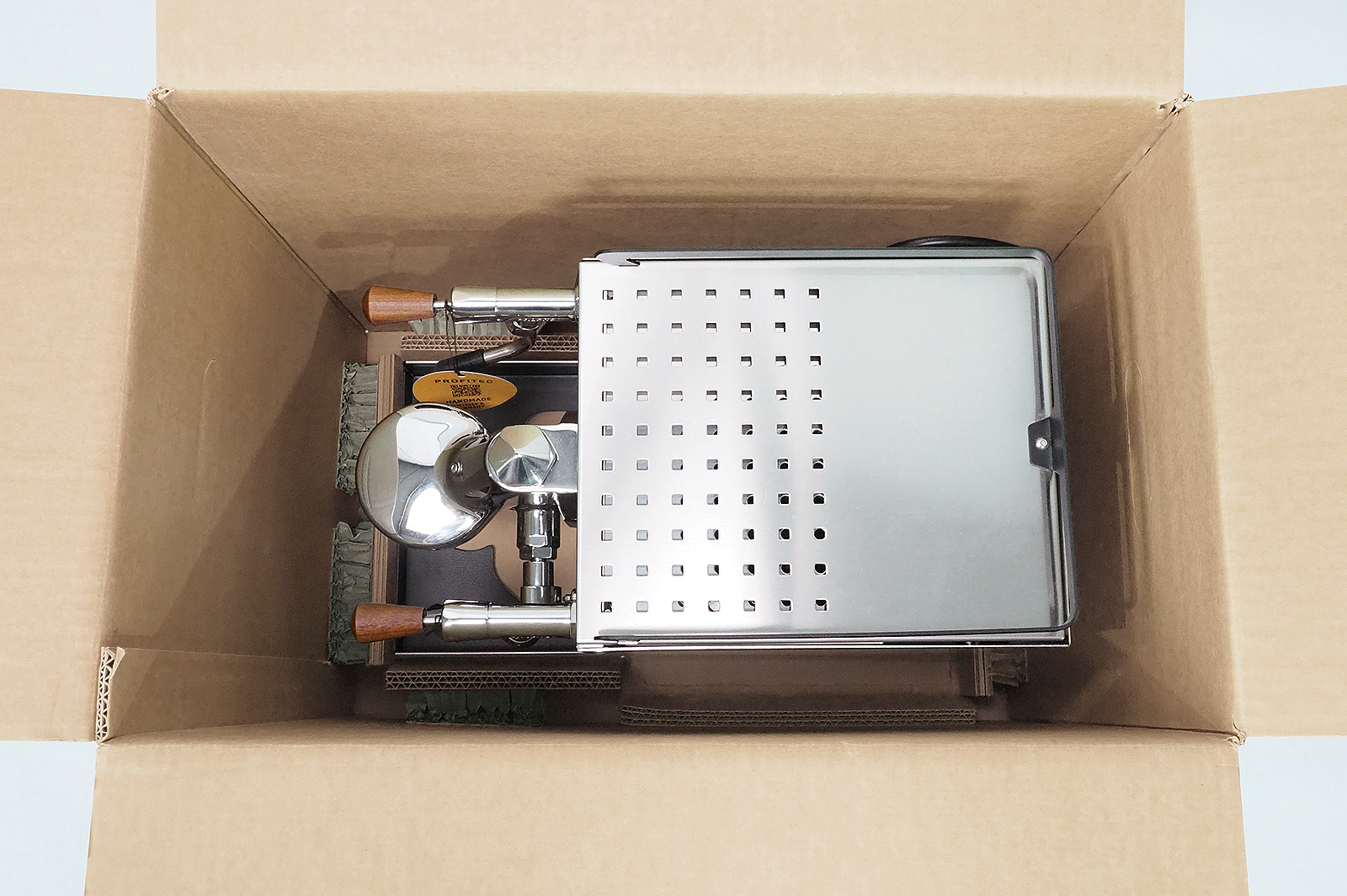 Siebträgermaschine im Karton mit passgenauem Bodenpolster aus Wellpappe und Rekkor®-Wabenpolster