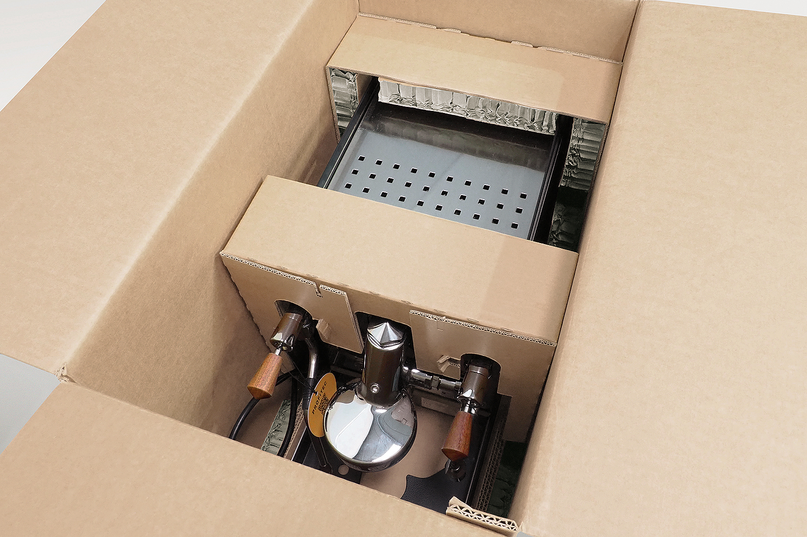 Seitliche 3D-Polster aus Rekkor®-Wabenpolster zur Stoßabsorption in der Versandverpackung einer Siebträgermaschine